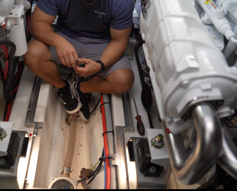 Capt Cabe, boat tech and ElectroSea servie manager, does 'boat yoga' to install an ElectroStrainer on a 56' foot Prestige boat. See engine room, ElectroStrainer, lines, and cords in the narrow space.